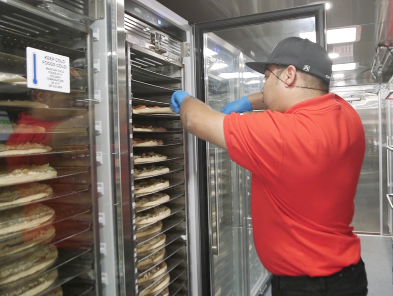 captain taking pizzas from refrigerator